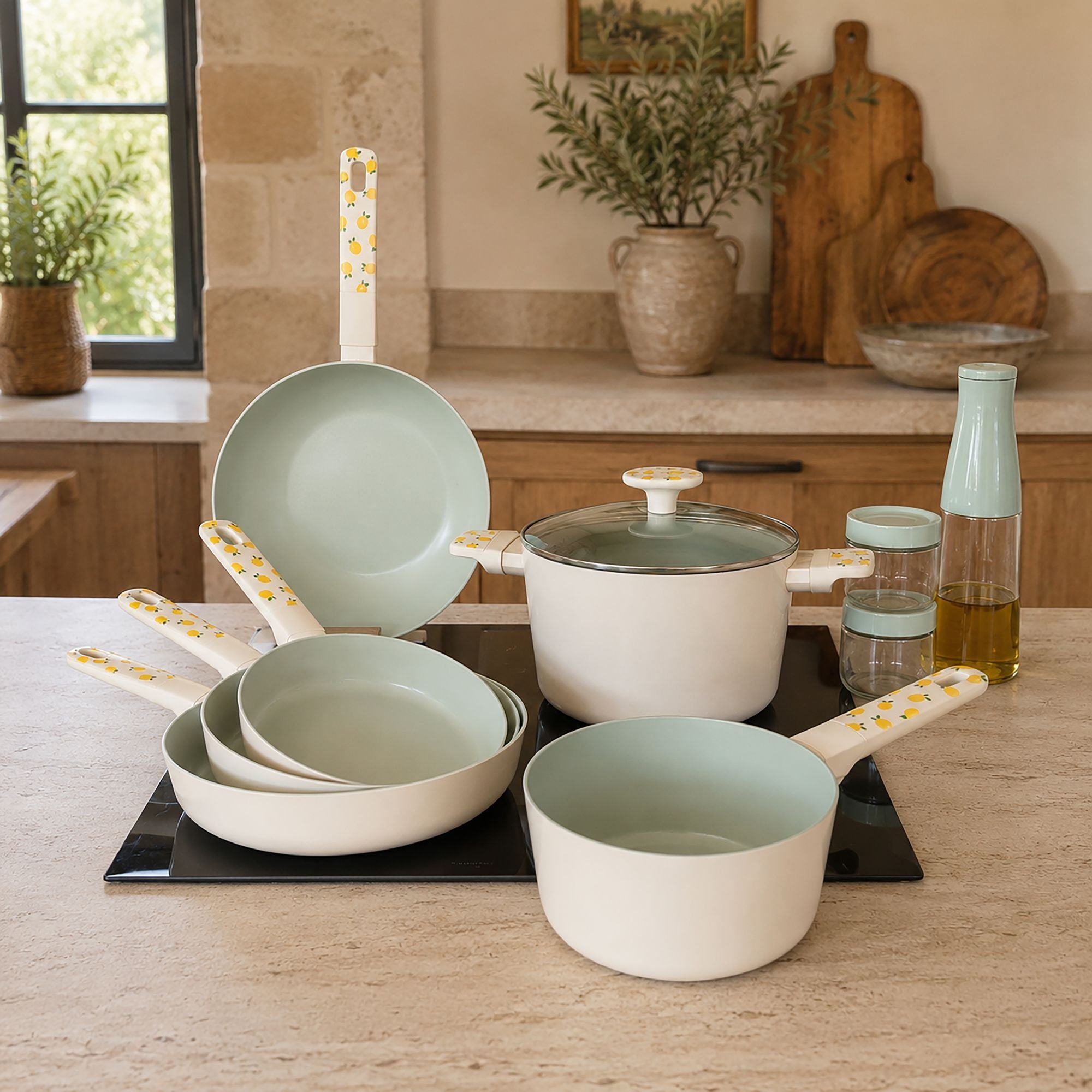 Set de 6 pièces en aluminium coloris citron avec casseroles, poêles et sauteuse, disposé sur plaque à induction dans cuisine moderne