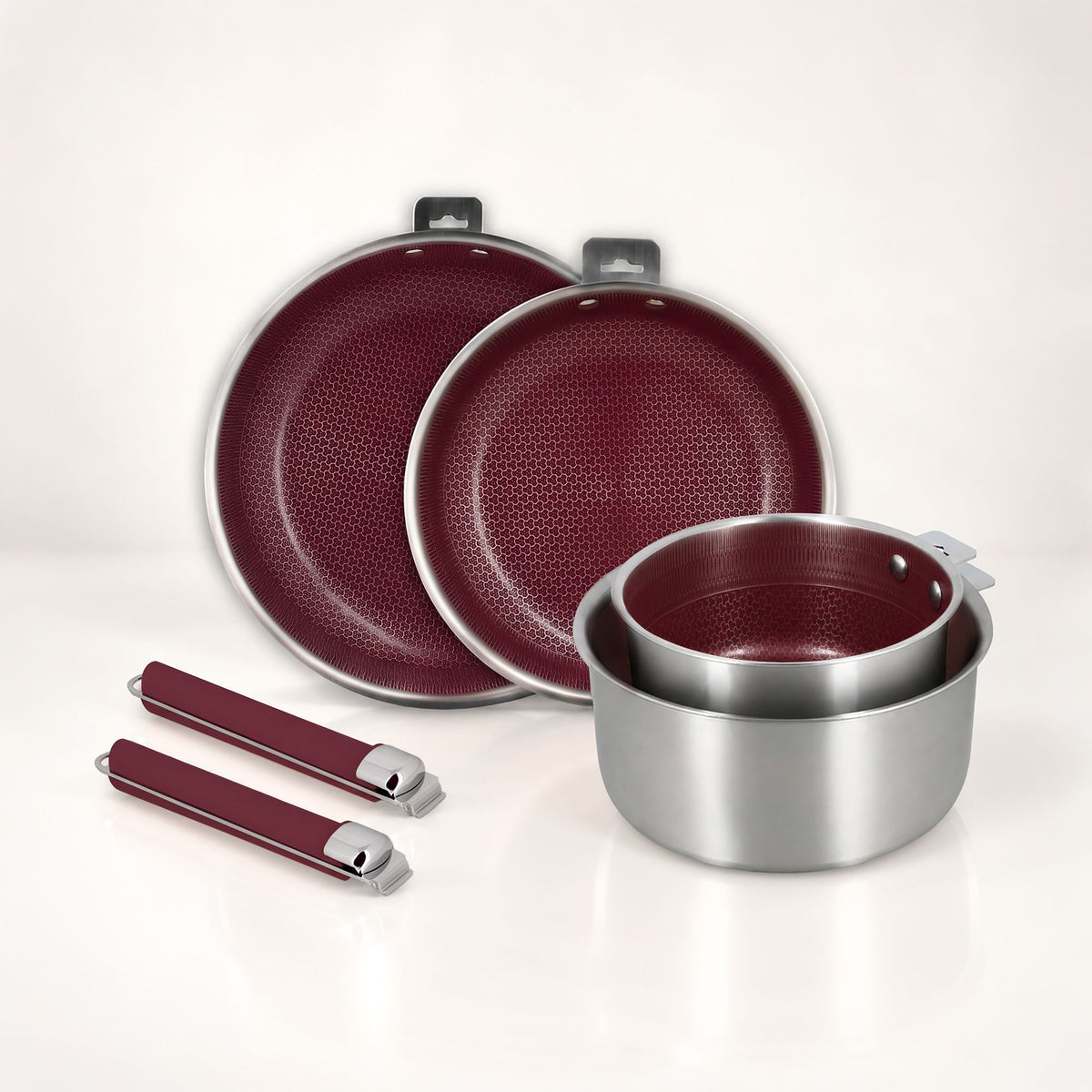Ensemble complet batterie de cuisine Aglaé 6 pièces : 2 poêles, 1 casserole et 2 poignées amovibles bordeaux, sur fond clair