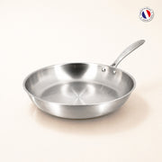 Poêle Triply 20cm en acier inoxydable triple couche Menastyl, vue de trois quarts sur fond clair