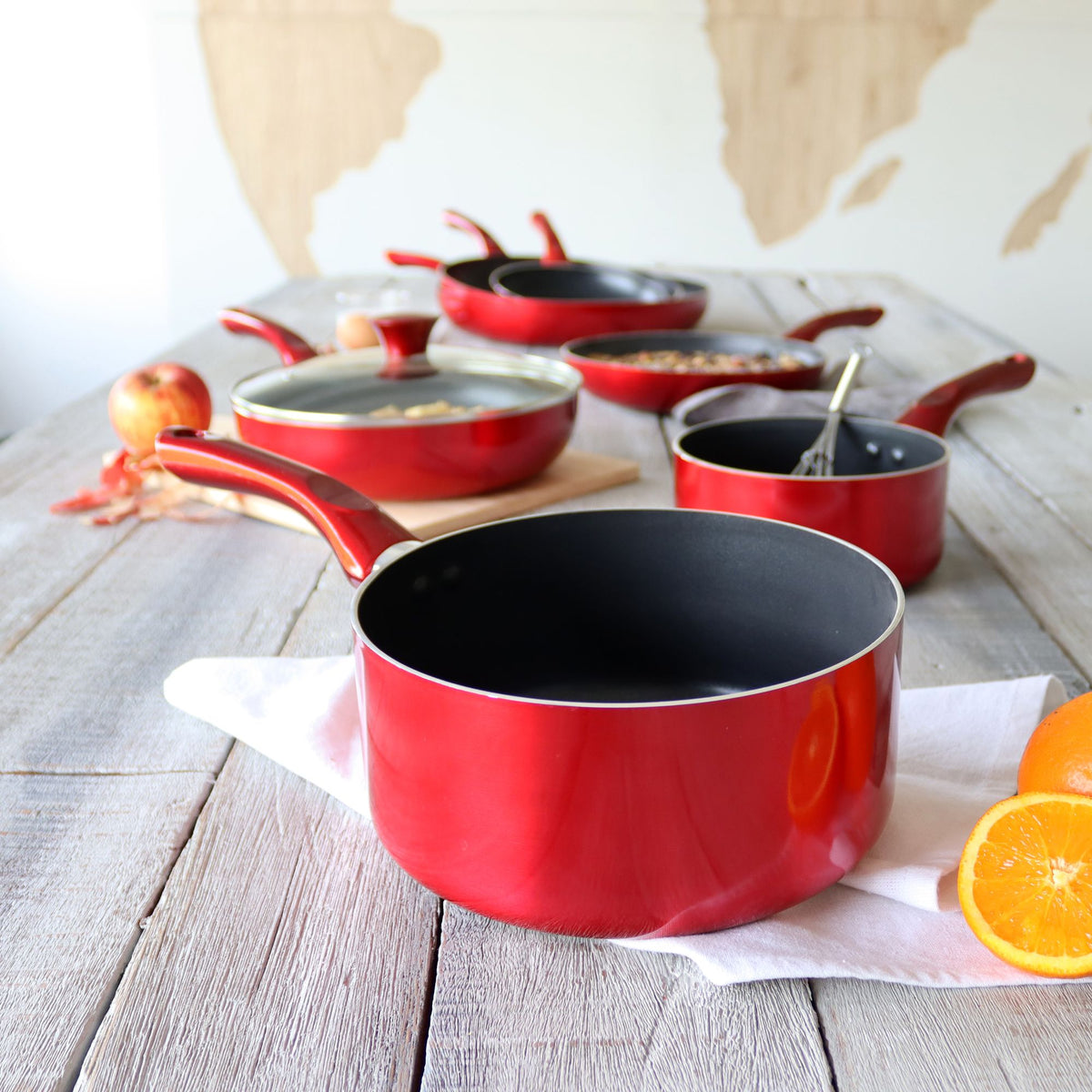 Collection de casseroles Cerise rouges 20 cm en aluminium avec intérieur antiadhésif noir, disposées sur table en bois