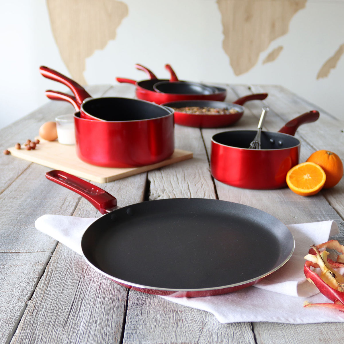 Set de casseroles et crêpière Cerise rouge métallique 25 cm sur table bois avec oranges et œufs