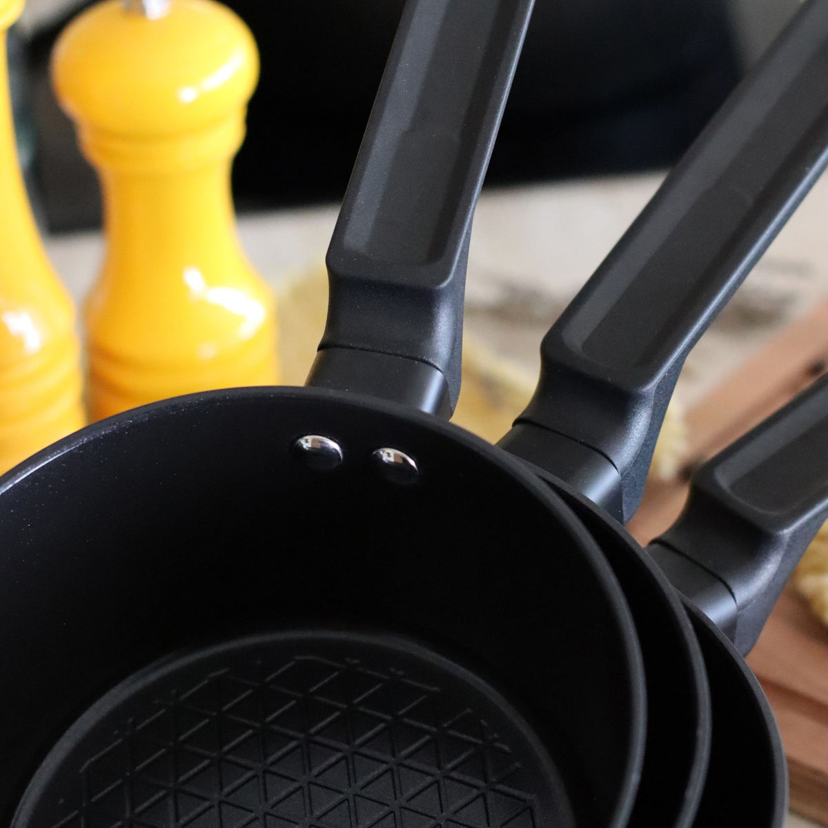 Vue détaillée de la casserole First 20 cm en aluminium noir avec motif anti-adhérent et trois antennas fixes