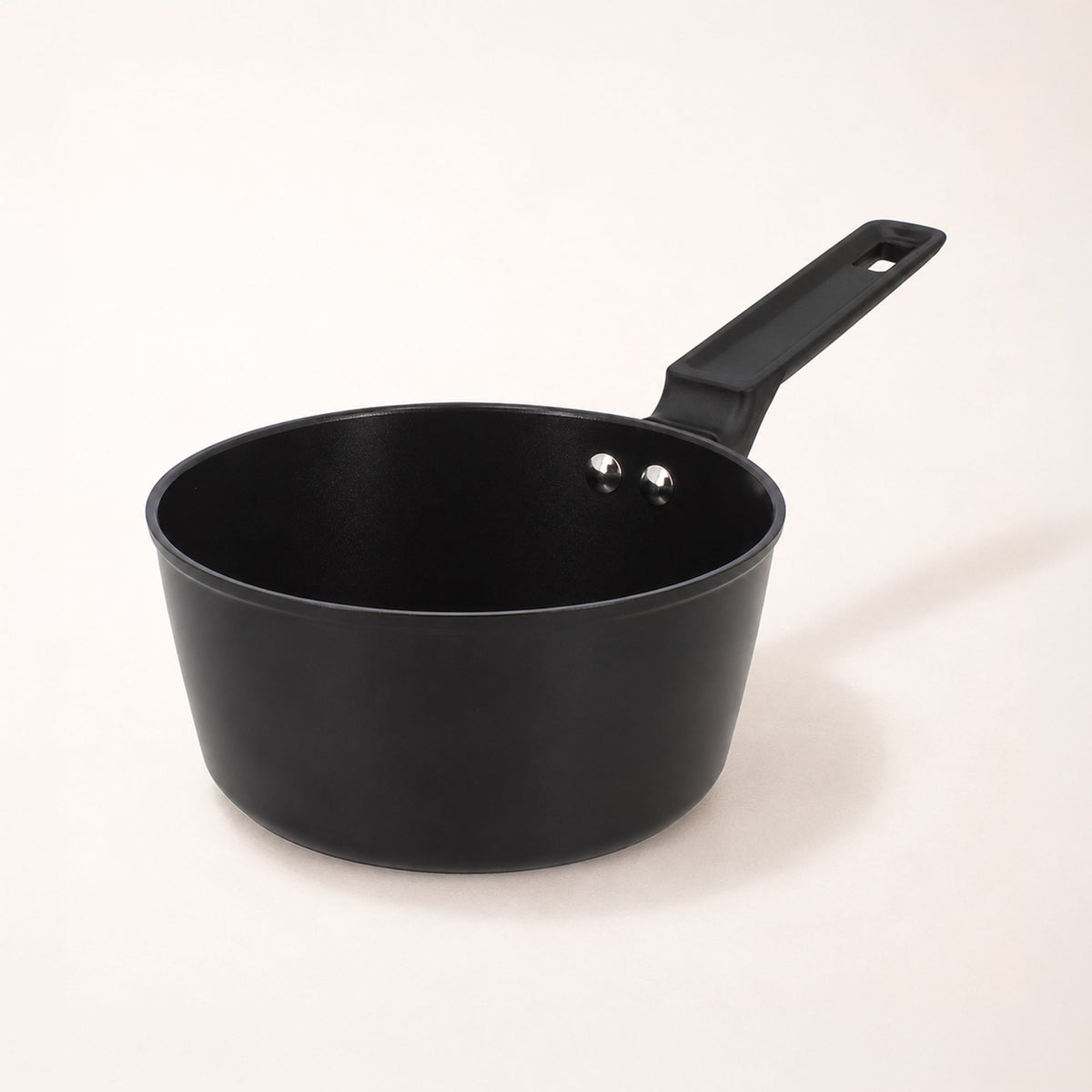 Casserole First 20 cm en aluminium noir avec poignée ergonomique, vue de trois-quarts sur fond clair