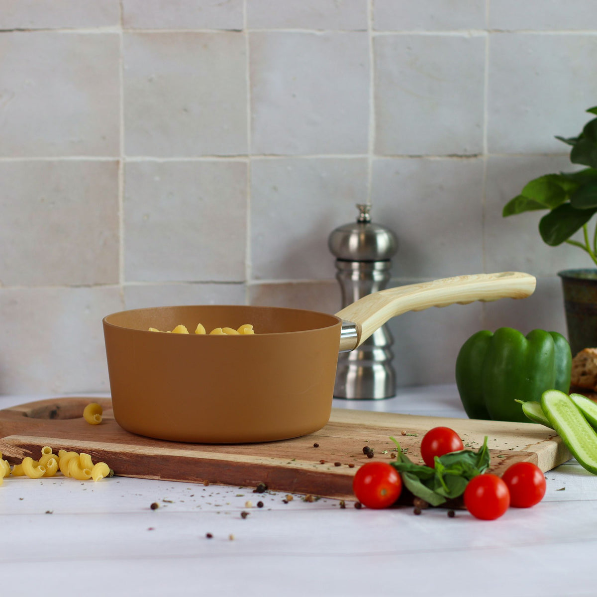 Casserole Colorama 18 cm ocre avec macaronis, mise en scène culinaire avec légumes frais sur planche bois