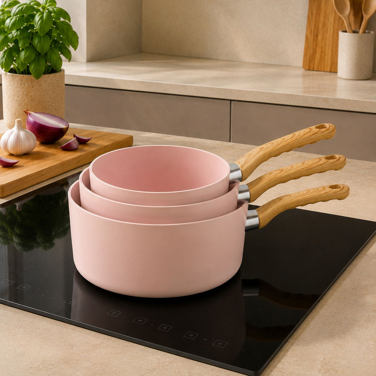 Trois casseroles roses empilées avec manches bois sur plaque induction, set Colorama vue d'ambiance cuisine moderne