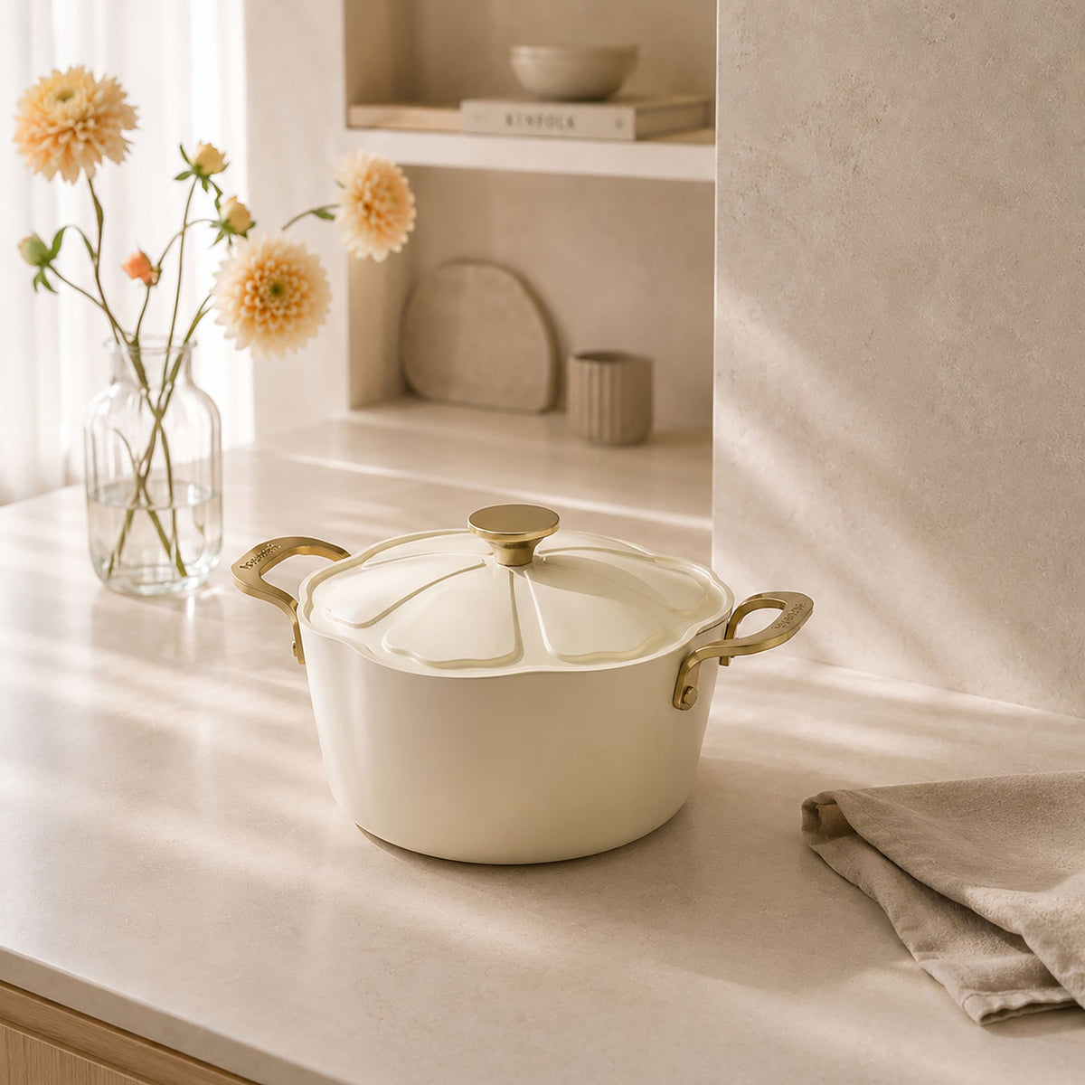 Faitout Dahlia 24 cm beige avec couvercle en verre, poignées dorées, ambiance lifestyle avec fleurs dahlia