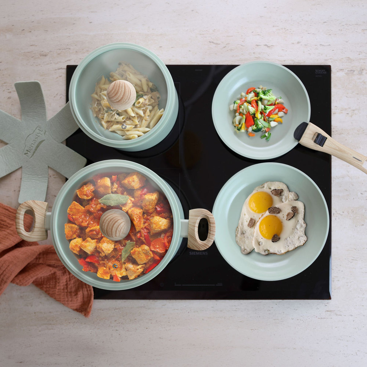 Vue de dessus du set de cuisson empilable Super Ball Colorama avec 4 plats préparés sur plaque de cuisson