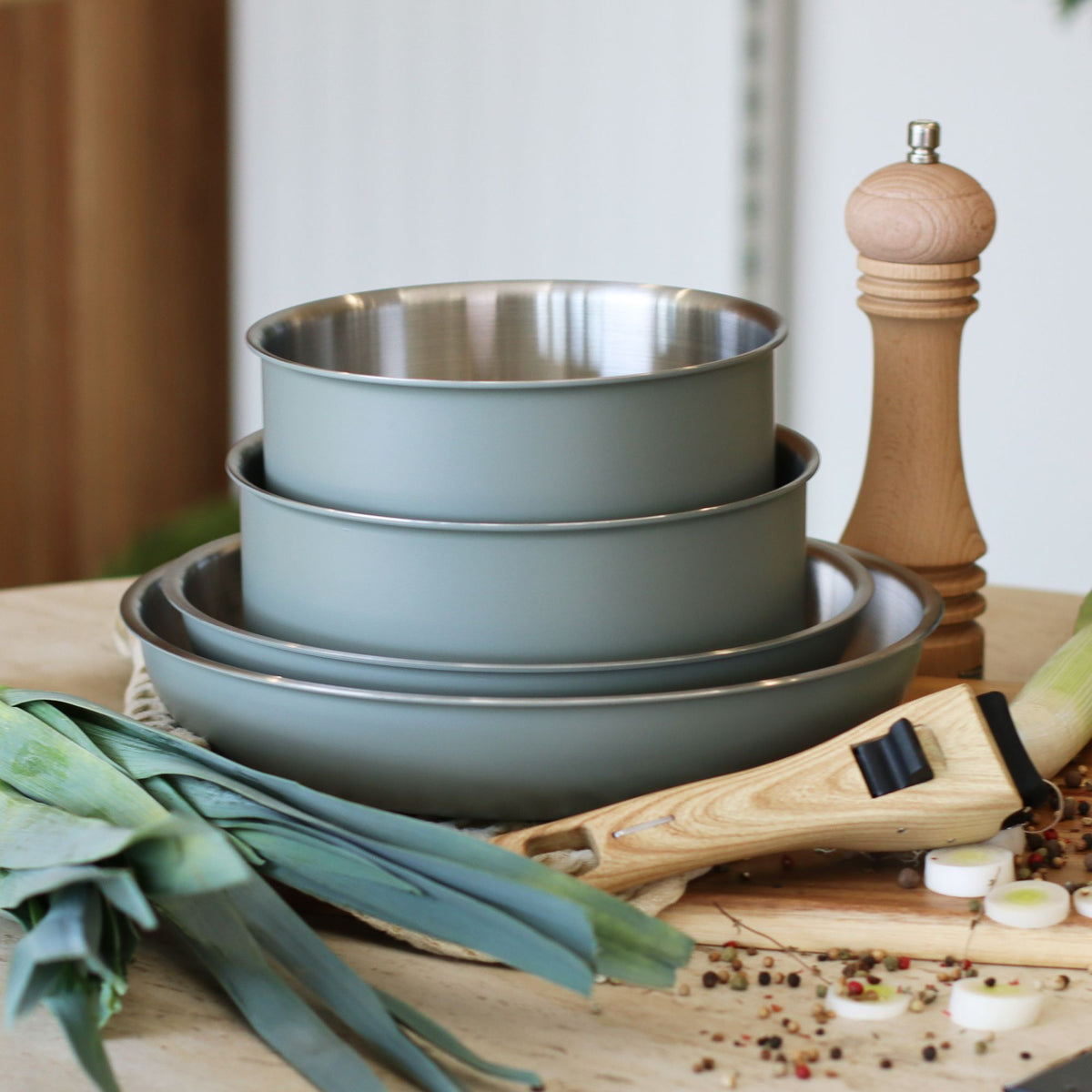 Set de 5 pièces Easynox avec casseroles inox gris mat empilées, poignée amovible et poivre en bois sur planche