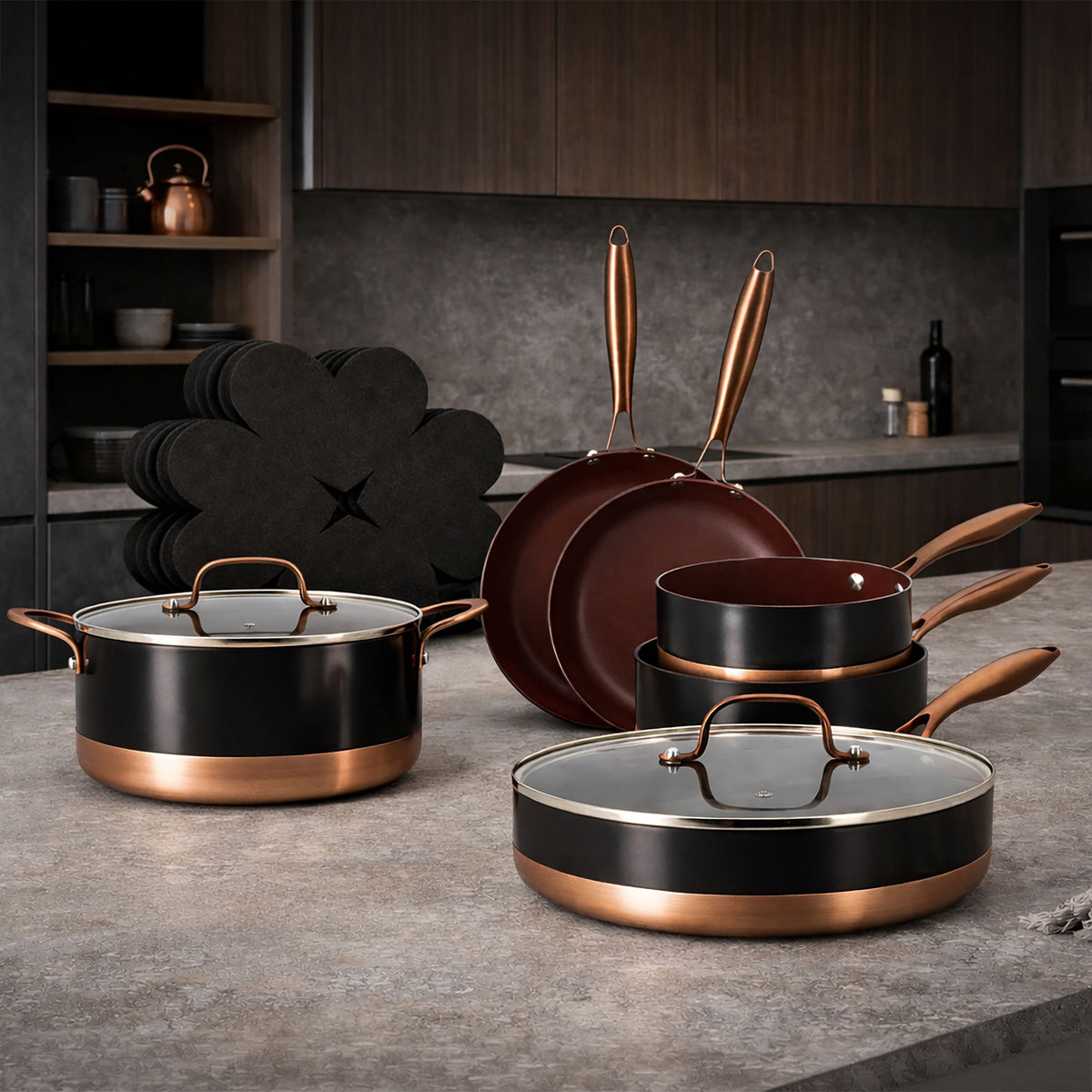 Set de 13 pièces Black Copper en aluminium recyclé noir et cuivre, disposé sur plan de travail gris de cuisine moderne