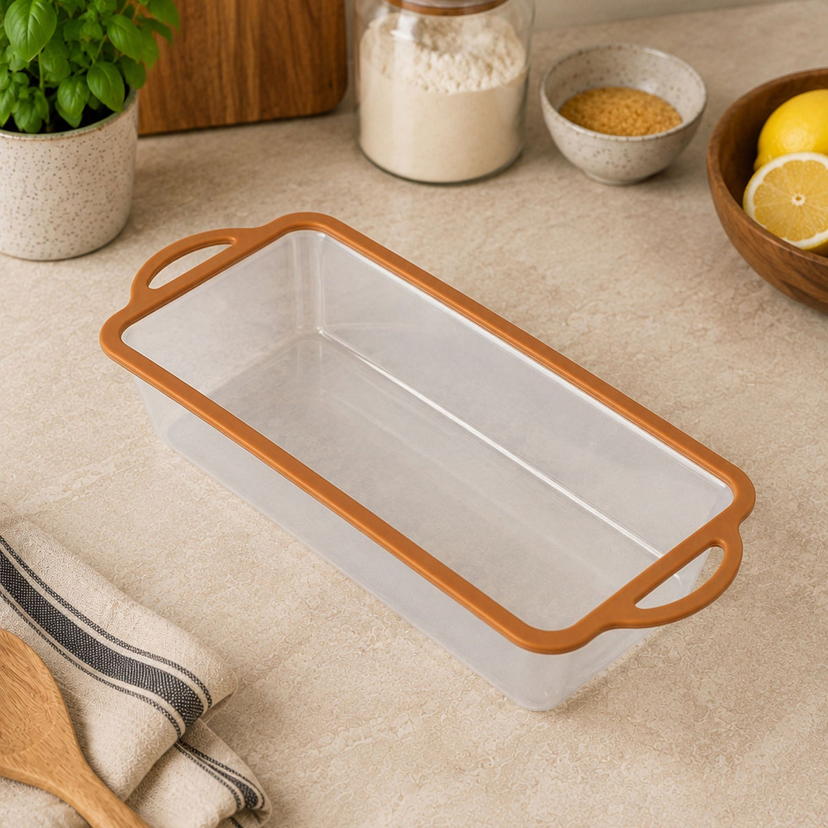 Moule à gâteau Mady transparent avec contour silicone orange, posé sur plan de travail avec ingrédients de pâtisserie