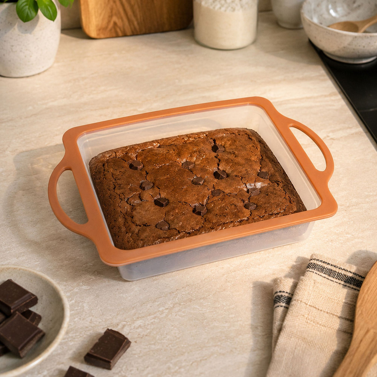 Moule à gâteau carré Mady 23x23cm avec brownie aux pépites de chocolat, cadre silicone orange sur plan de travail