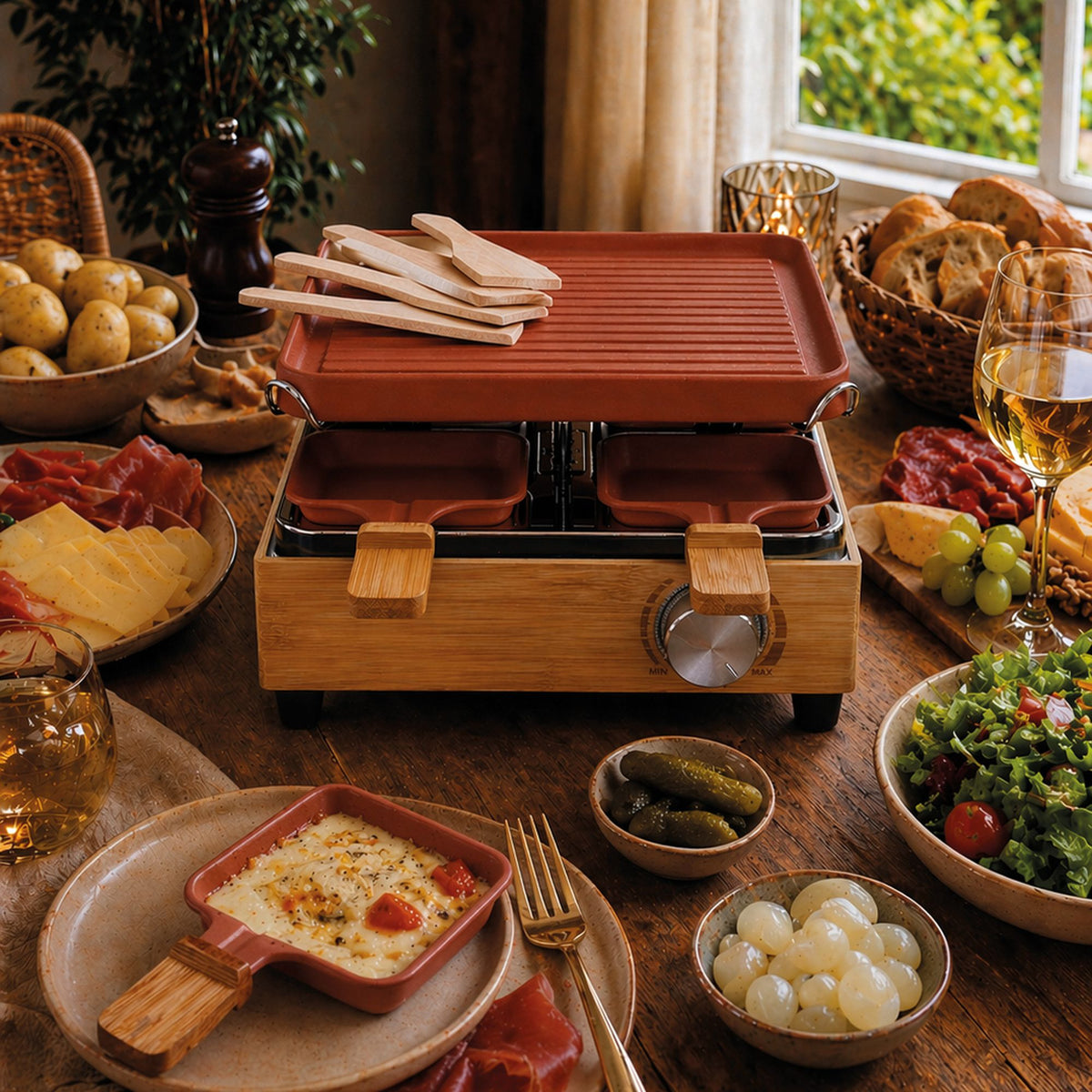 Table dressée avec appareil à raclette 4 personnes bambou et aluminium, entouré de fromages, charcuteries et accompagnements