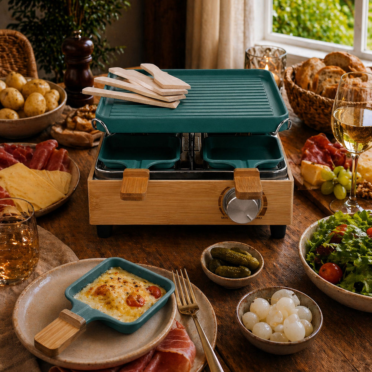 Appareil à raclette 4 personnes en bambou et aluminium bleu canard, table dressée avec fromage et charcuterie