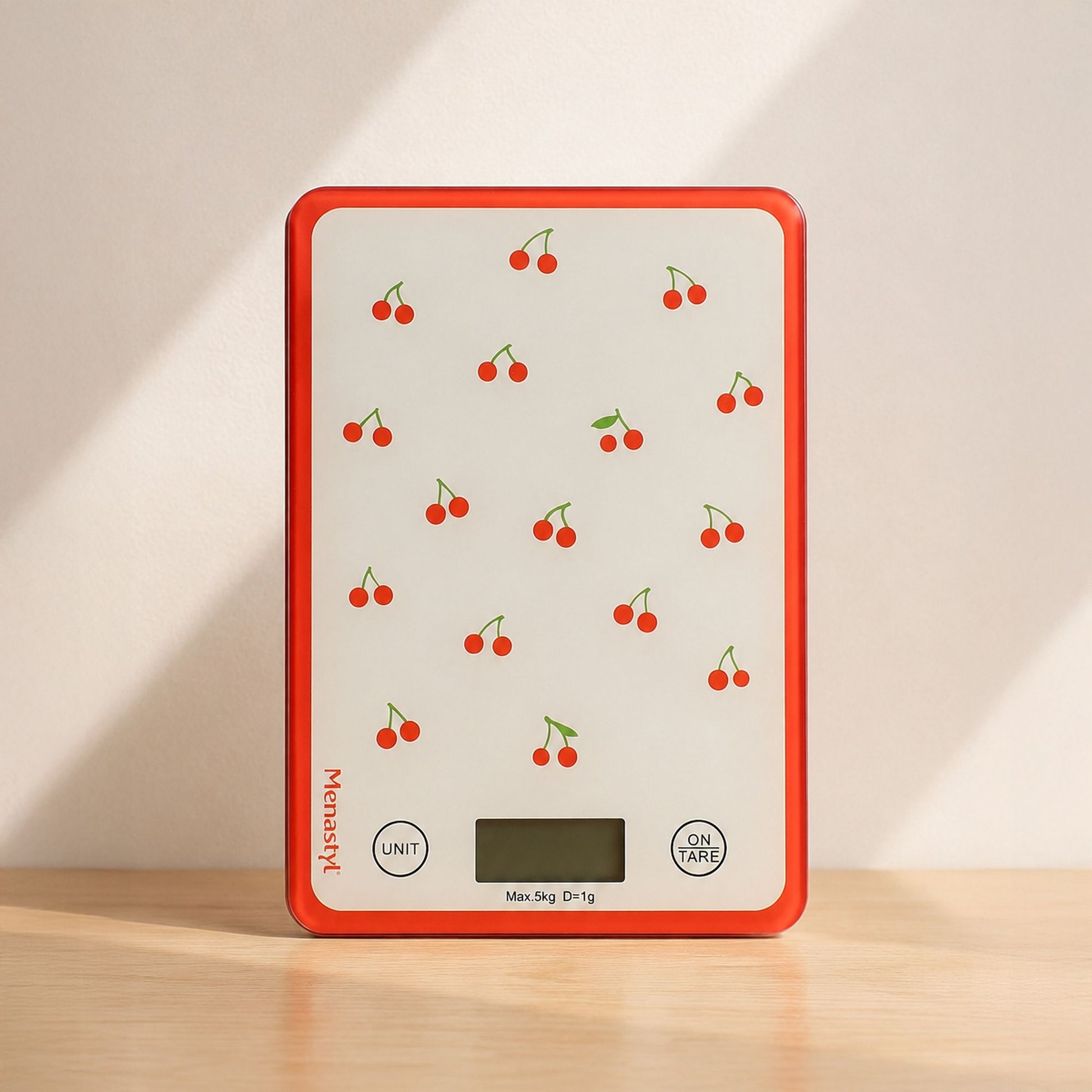 Balance de cuisine électronique motif cerises rouges, fond blanc cassé avec bordure rouge corail, posée sur table en bois