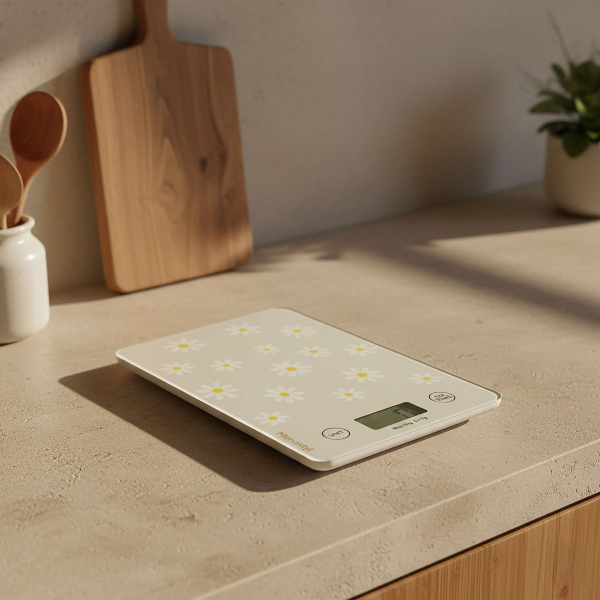 Balance de cuisine électronique motif marguerites blanches et jaunes, posée sur plan de travail beige avec décor cuisine scandinave
