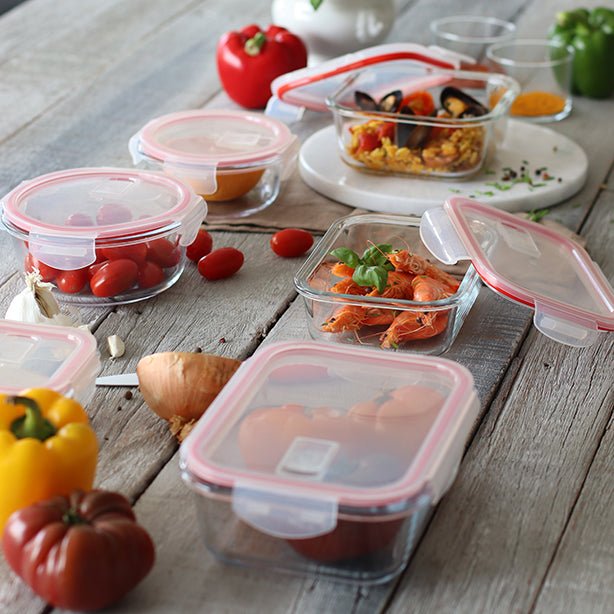 Ensemble de boîtes hermétiques Clémentine en verre avec couvercles roses contenant des aliments frais sur table en bois rustique