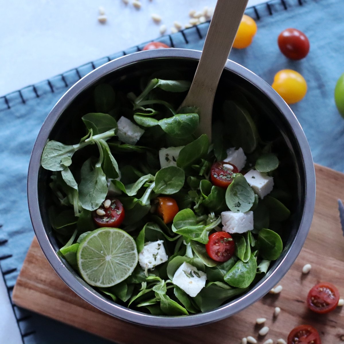 Bol à mélanger inox 22cm contenant une salade verte avec tomates cerises, feta et citron vert