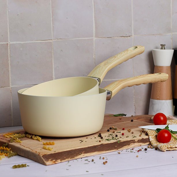 Casserole Colorama 18 cm crème avec manche bois, posée sur planche en bois avec ingrédients de cuisine