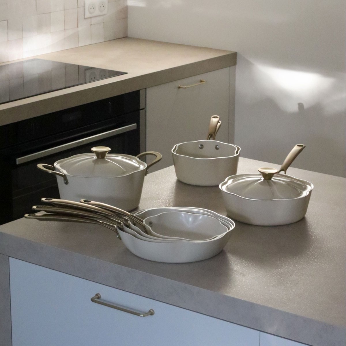 Collection casseroles et poêles Dahlia en aluminium recyclé beige avec couvercles en verre sur plan de travail cuisine