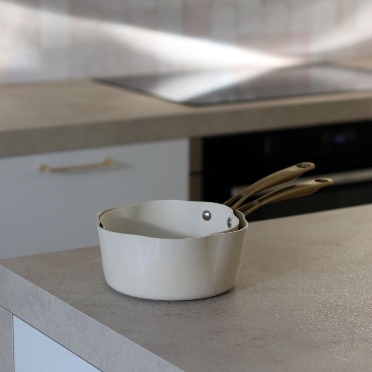 Casserole Dahlia 18 cm beige en aluminium recyclé posée sur plan de travail, vue de face avec poignée
