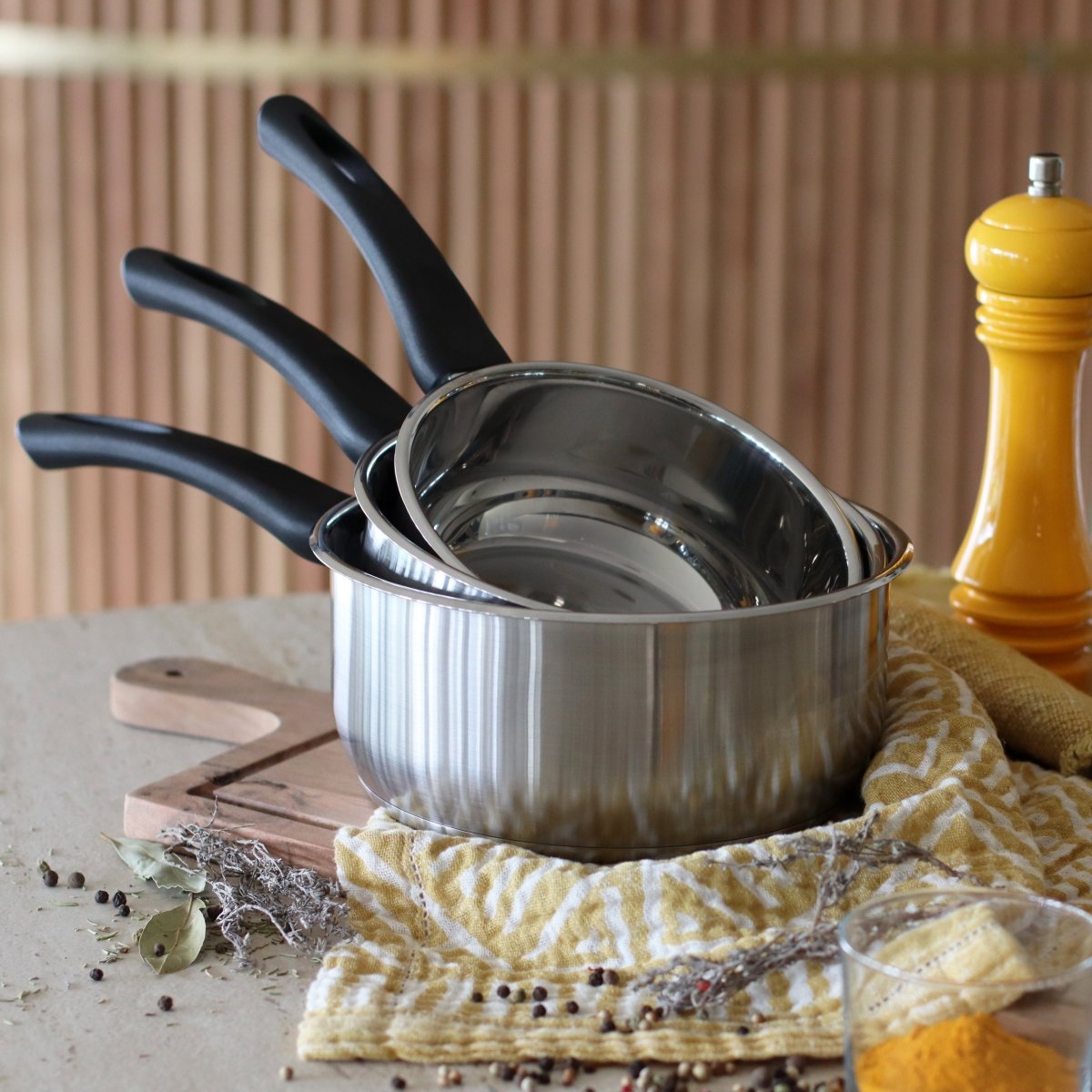 Set de trois casseroles First empilées en acier inoxydable avec manches noirs, ambiance cuisine naturelle