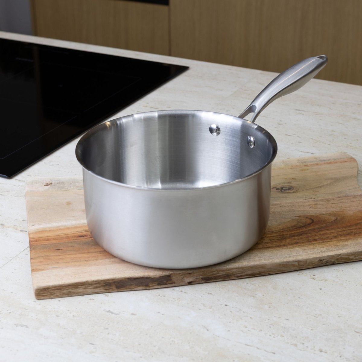 Casserole Trinox 20cm en acier inoxydable posée sur planche bois, vue intérieur et profil avec manche