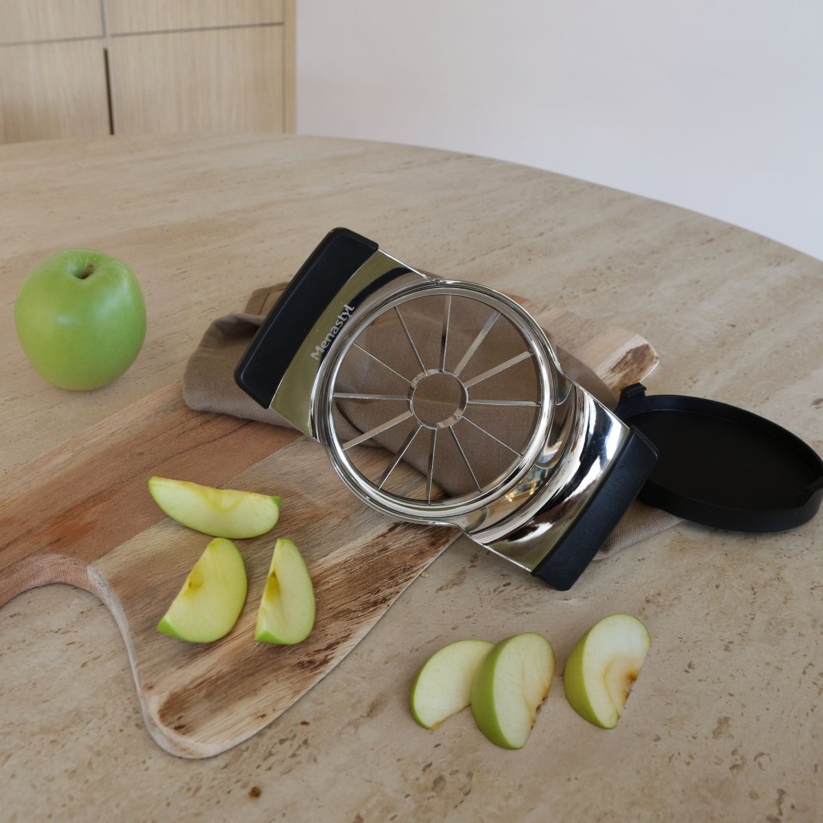Coupe-pomme en acier inoxydable avec poignées noires, tranches de pomme verte sur planche bois