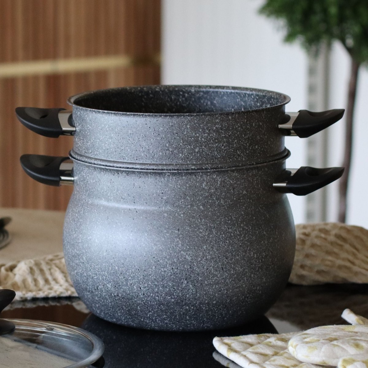 Deux couscoussiers en aluminium granité gris empilés, avec anses noires et couvercle en verre à côté