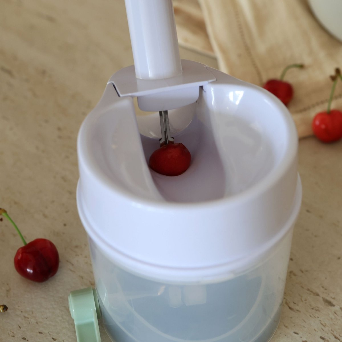 Dénoyauteur à cerises en action, cerise sous le poinçon, mécanisme à ressort en plastique blanc