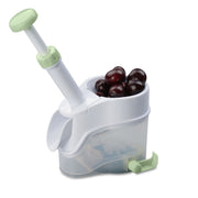 Dénoyauteur à cerises Menastyl en plastique blanc et vert, avec mécanisme à ressort et récipient transparent contenant des cerises