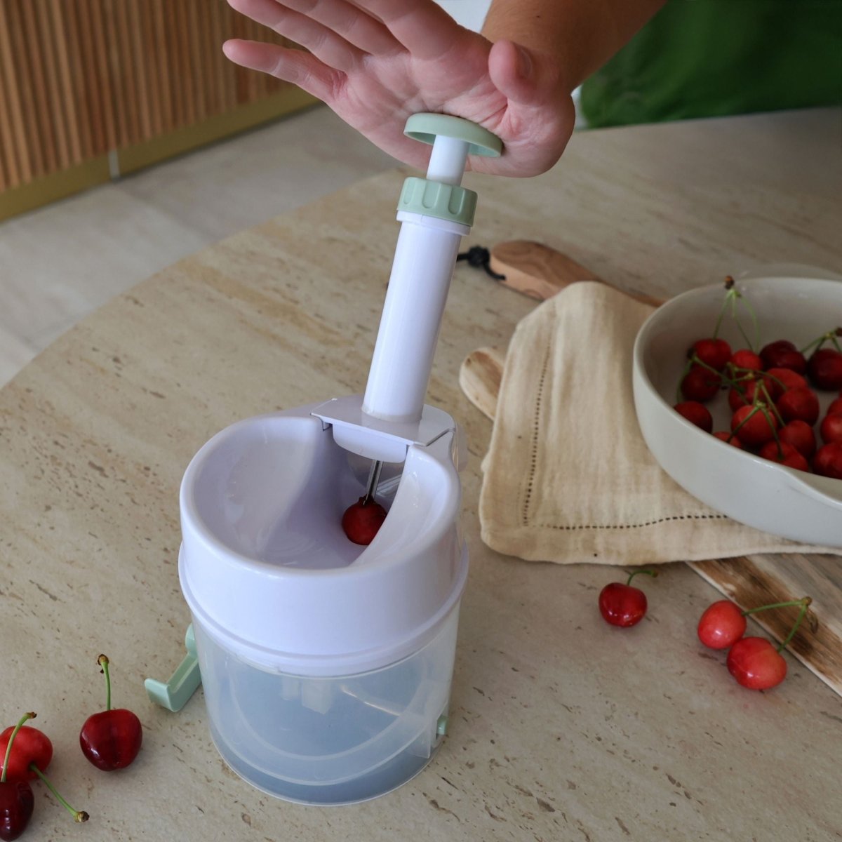 Utilisation du dénoyauteur à cerises en plastique blanc, main actionnant le mécanisme à ressort sur cerise