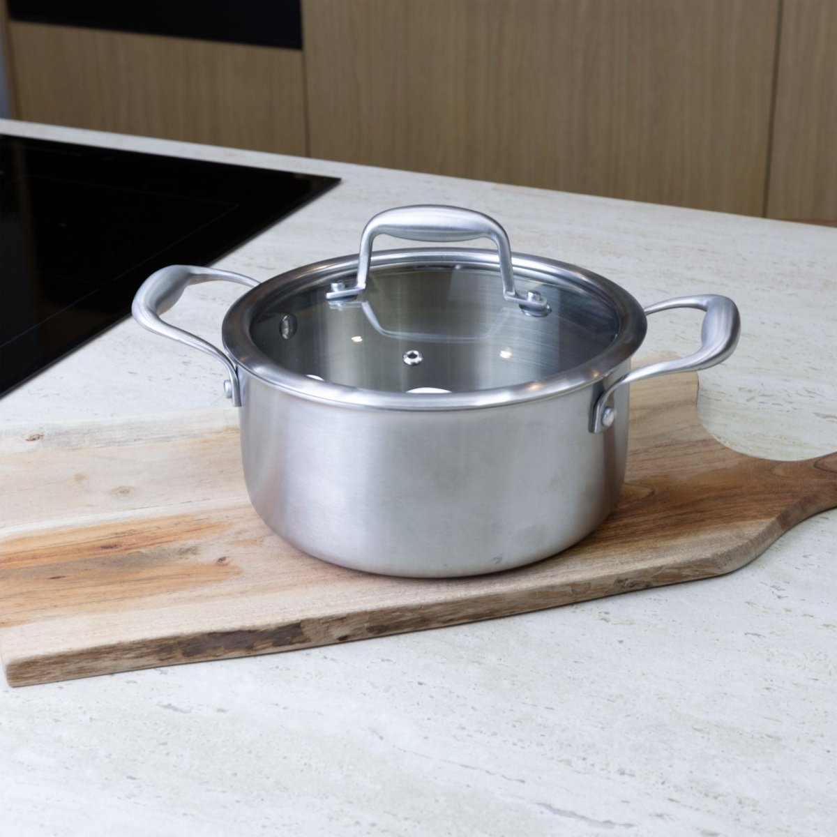 Faitout Trinox 20cm en acier inoxydable avec couvercle en verre, posé sur planche bois et plan de travail cuisine