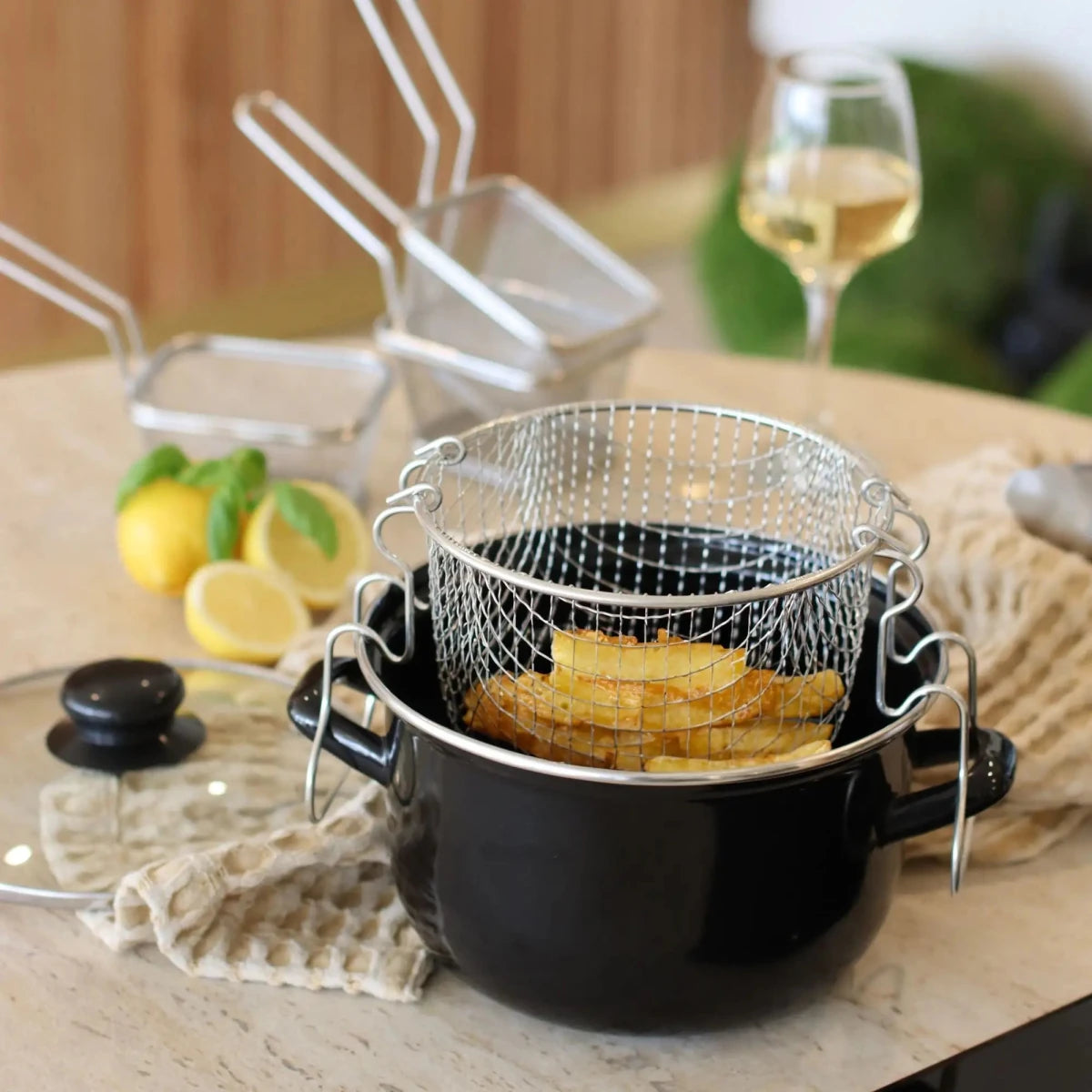 Friteuse en acier émaillé noir 20 cm avec panier inox et lemons frits, vue détail sur table en bois