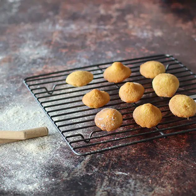 Grille à pâtisserie Amandine en acier carbone avec petits choux dorés refroidissant sur fond rustique