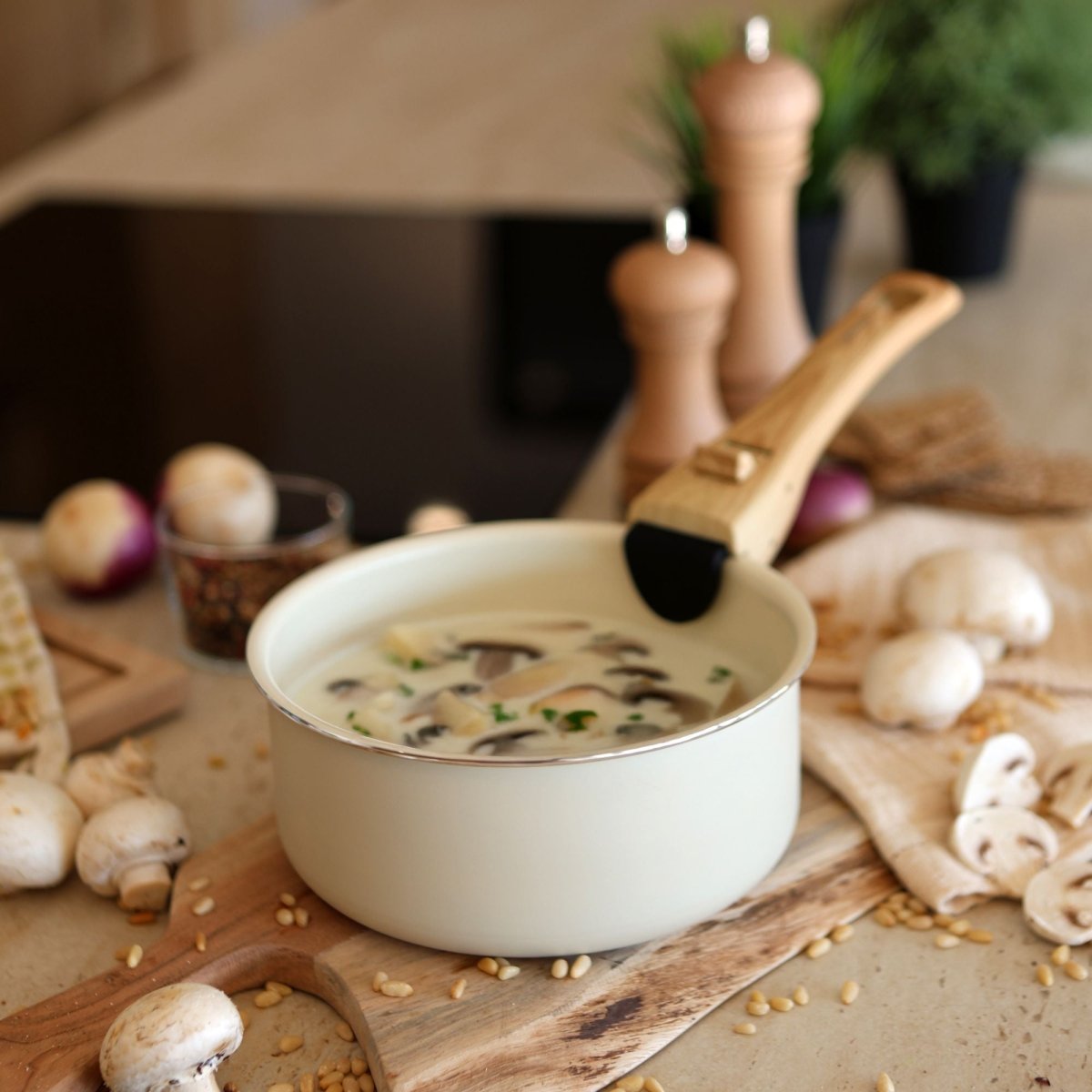 Bol de soupe aux champignons avec casserole colorama crème, ustensiles en bois et ingrédients frais sur planche