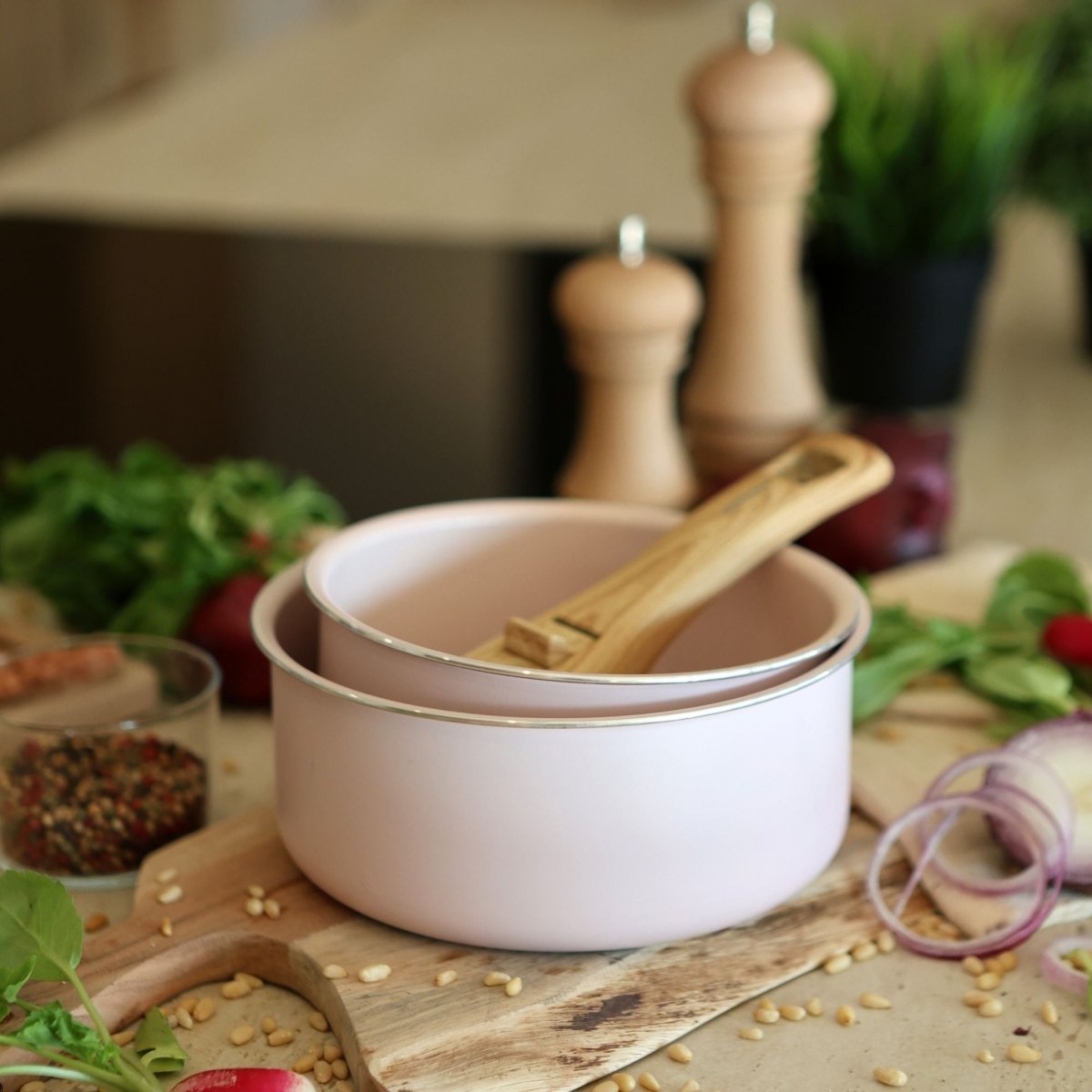 Lot de 2 casseroles Colorama 16 et 18 cm rose poudré avec poignée amovible bois, sur planche cuisine avec ingrédients