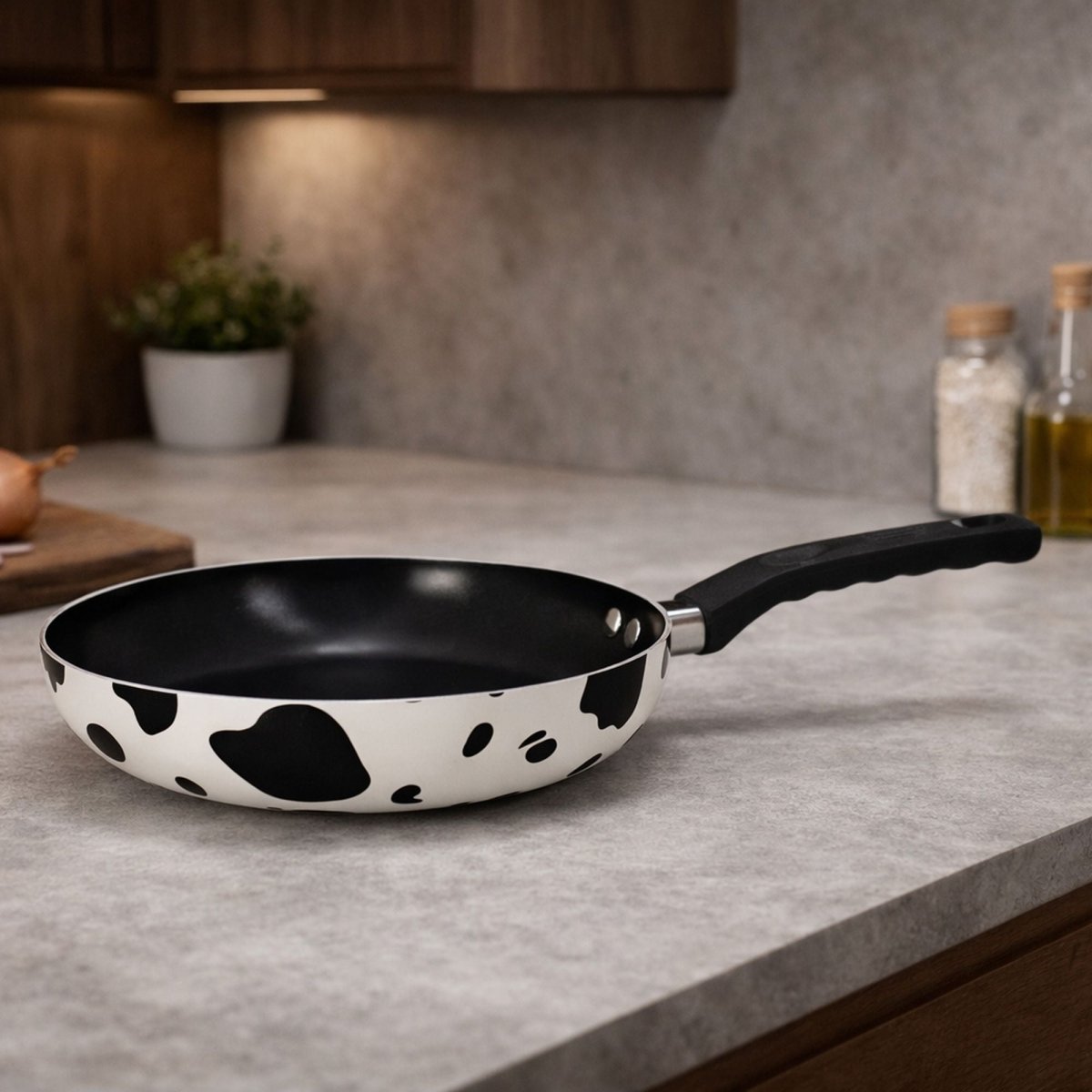 Poêle en aluminium motif vache blanc et noir avec revêtement céramique, posée sur plan de travail gris cuisine moderne