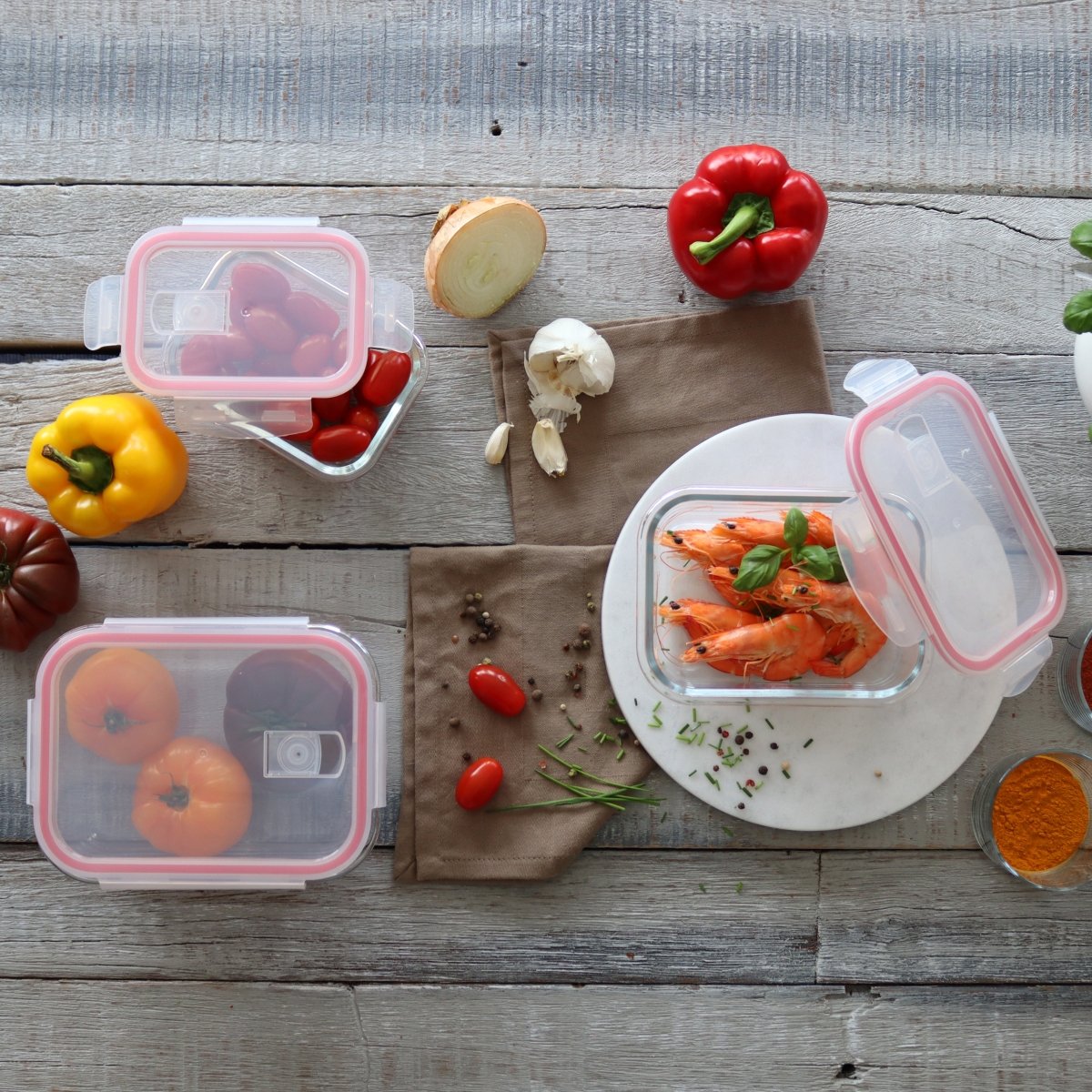 Vue détail boîtes hermétiques rectangulaires en verre avec aliments frais, couvercles roses, sur table en bois rustique