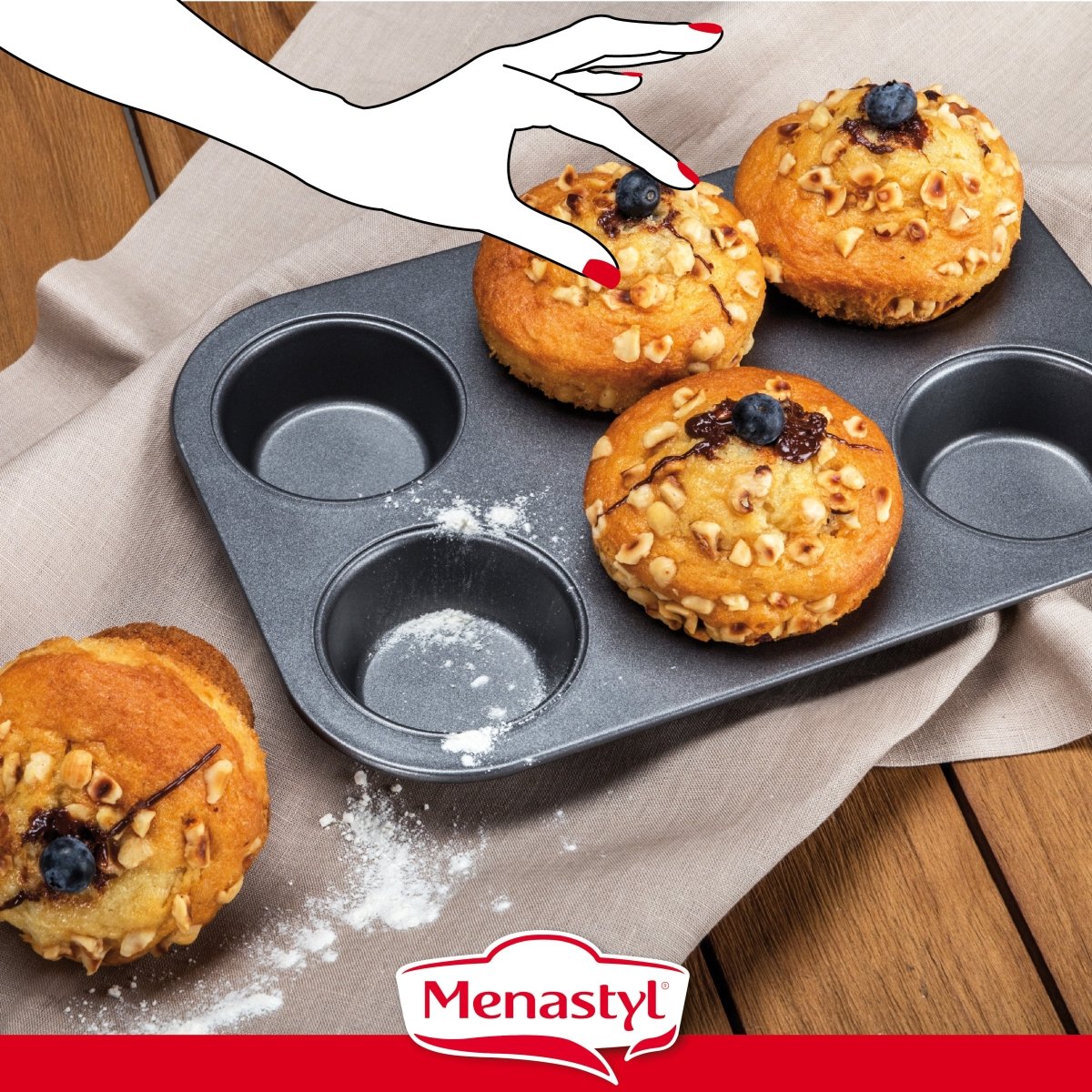 Main illustrée avec ongles rouges saisissant un muffin doré aux pépites sur moule à 6 muffins en acier carbone antiadhésif