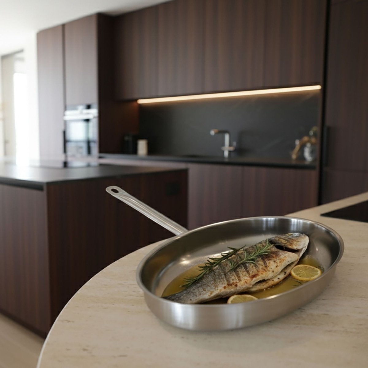Poêle à poisson ovale en acier inoxydable avec dorade grillée, romarin et citron dans cuisine moderne