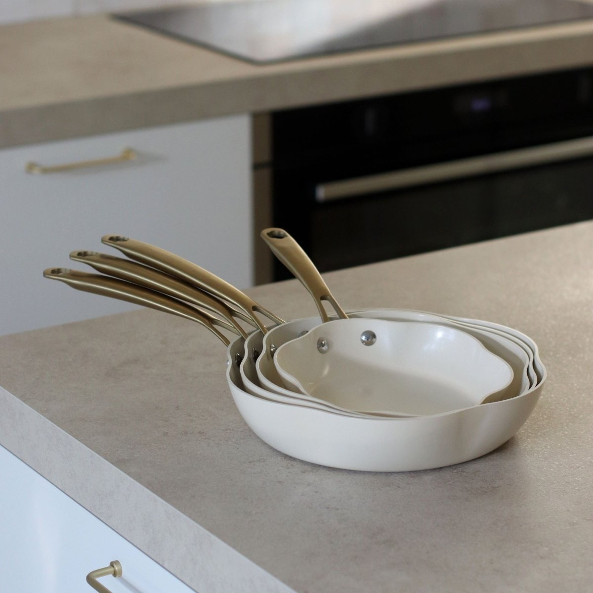 Set de 4 poêles Dahlia beige empilées, aluminium recyclé, vue sur plan de travail cuisine moderne