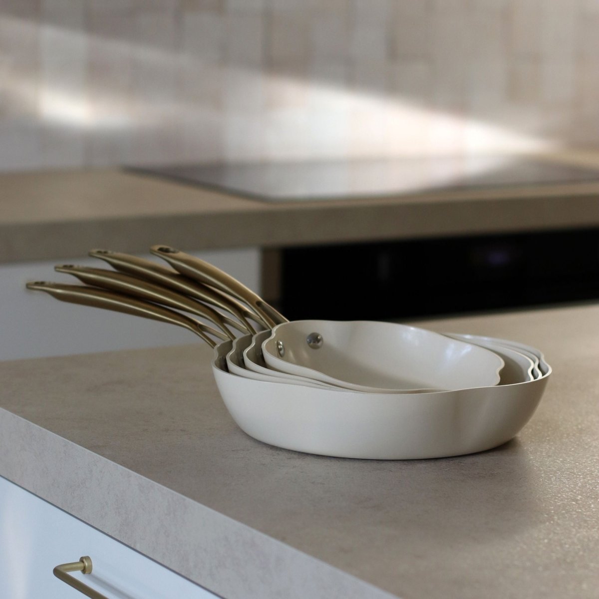 Set de 5 poêles Dahlia en aluminium recyclé beige empilées, vue sur plan de travail cuisine moderne