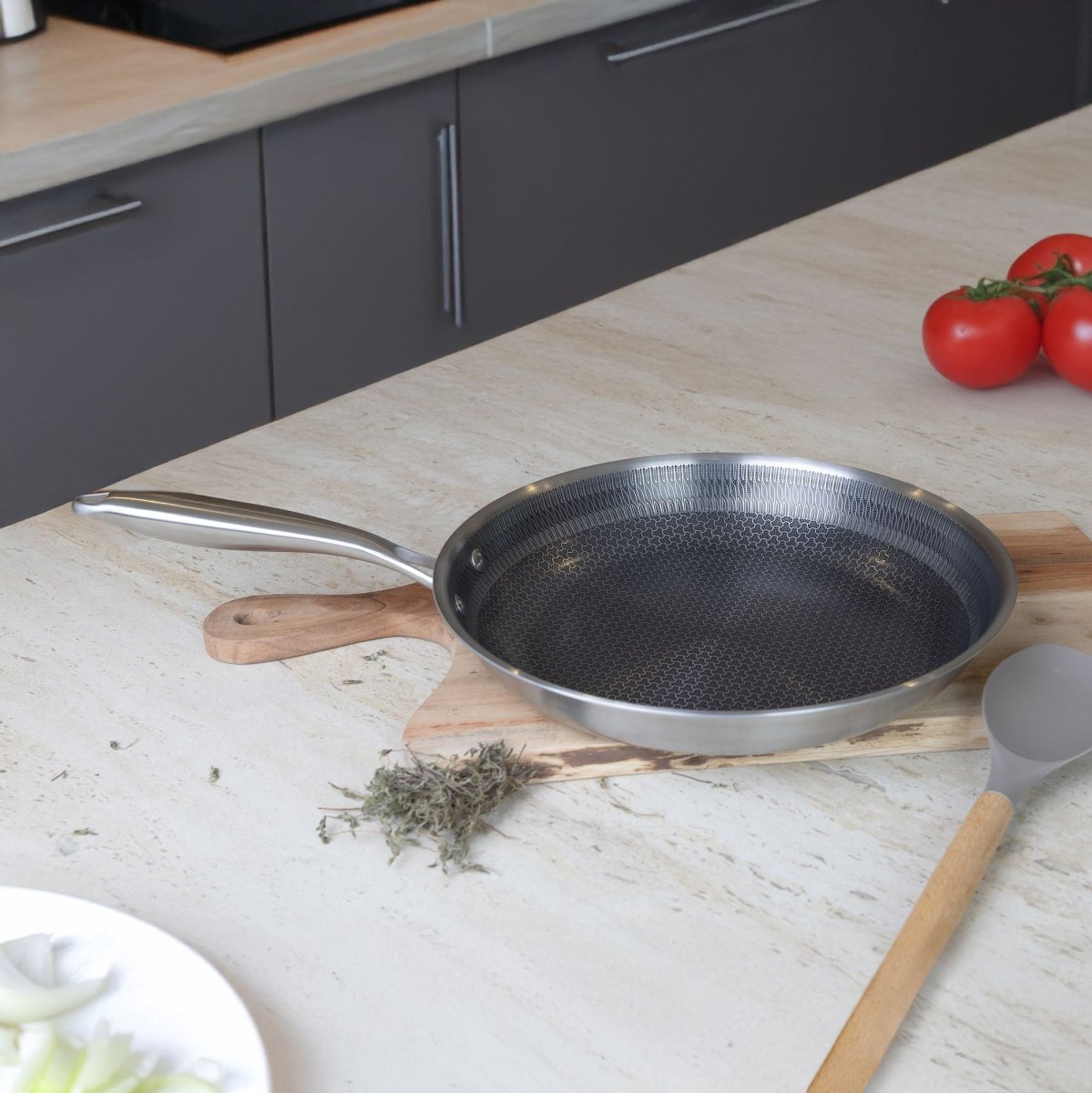 Poêle Trinox 24cm en inox avec revêtement antiadhésif, posée sur planche bois dans cuisine moderne