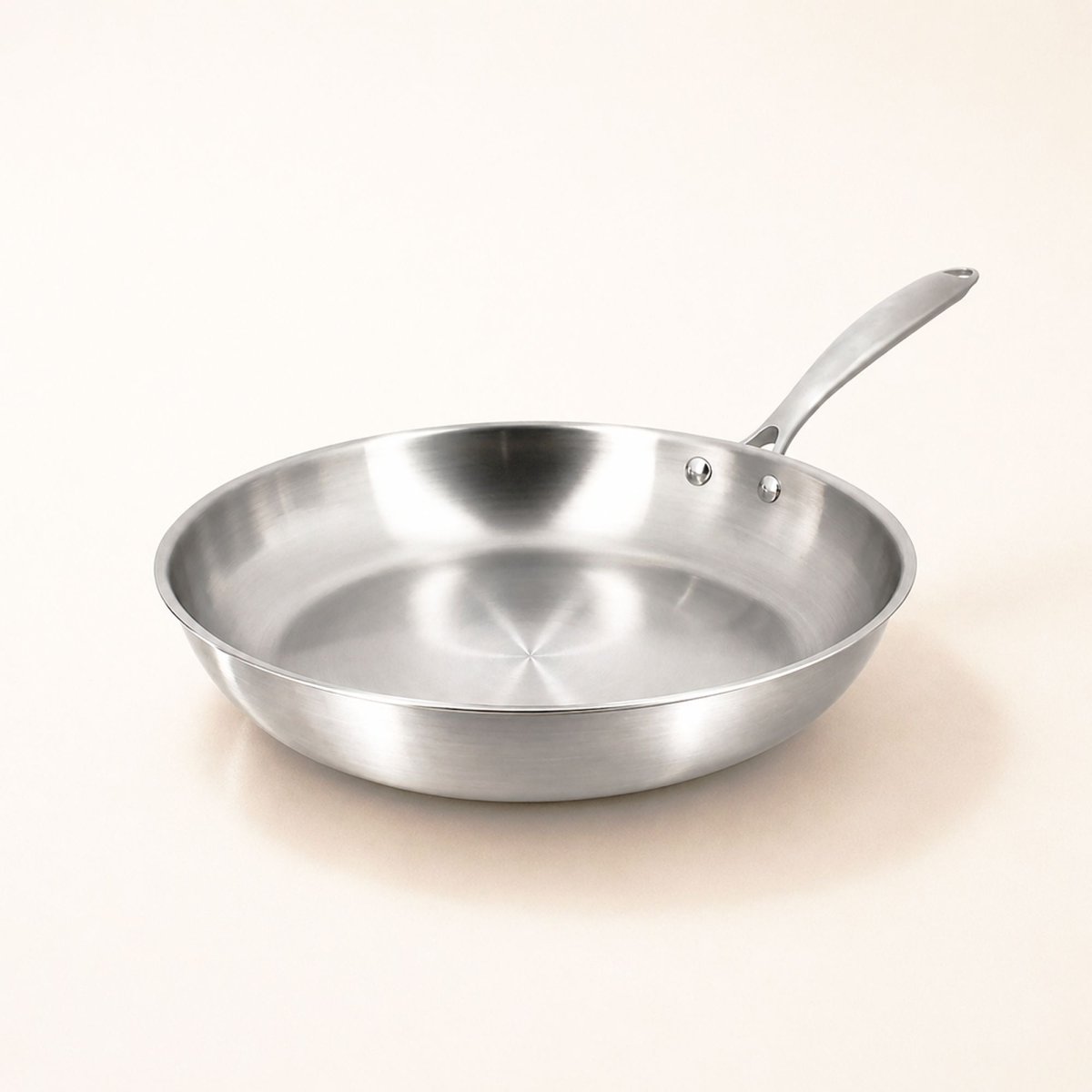 Poêle Triply 20cm en acier inoxydable triple couche Menastyl, vue de trois quarts sur fond clair