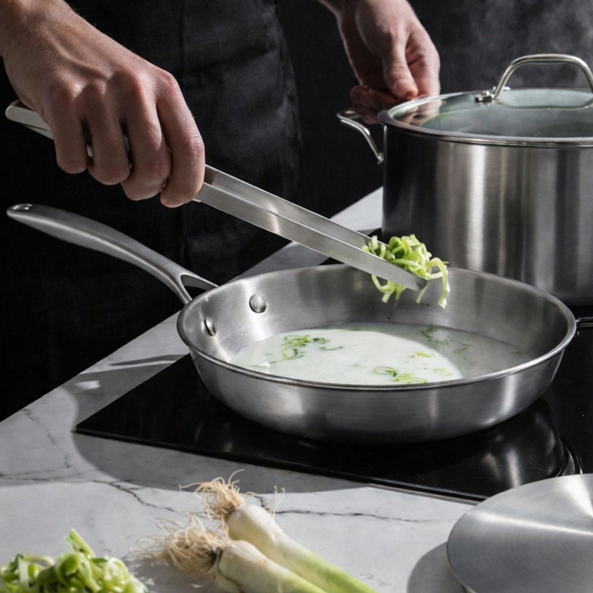 Poêle Triply inox 32cm en cuisson, ajout de légumes verts avec ustensile de cuisine, vapeur visible