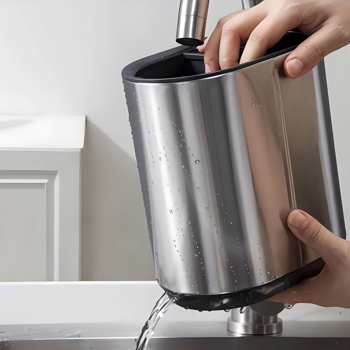 Porte-ustensiles en inox cylindrique avec couvercle noir, vidé dans un évier blanc