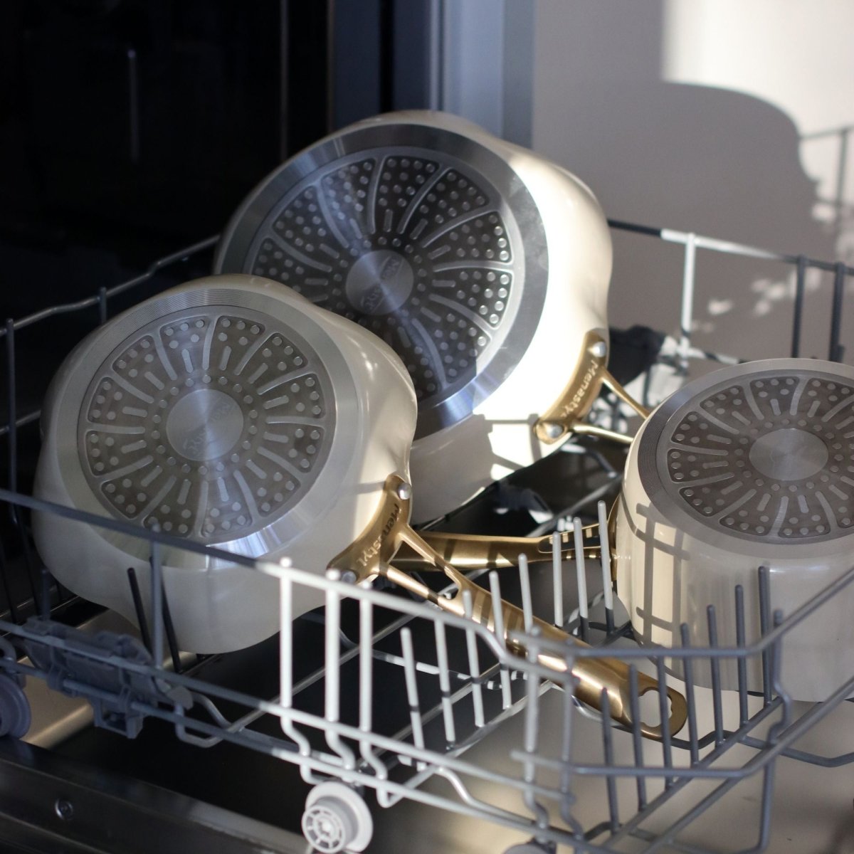 Sauteuses Dahlia 24 cm beige et dorées dans un lave-vaisselle ouvert, vue intérieure du couvercle à motif radial
