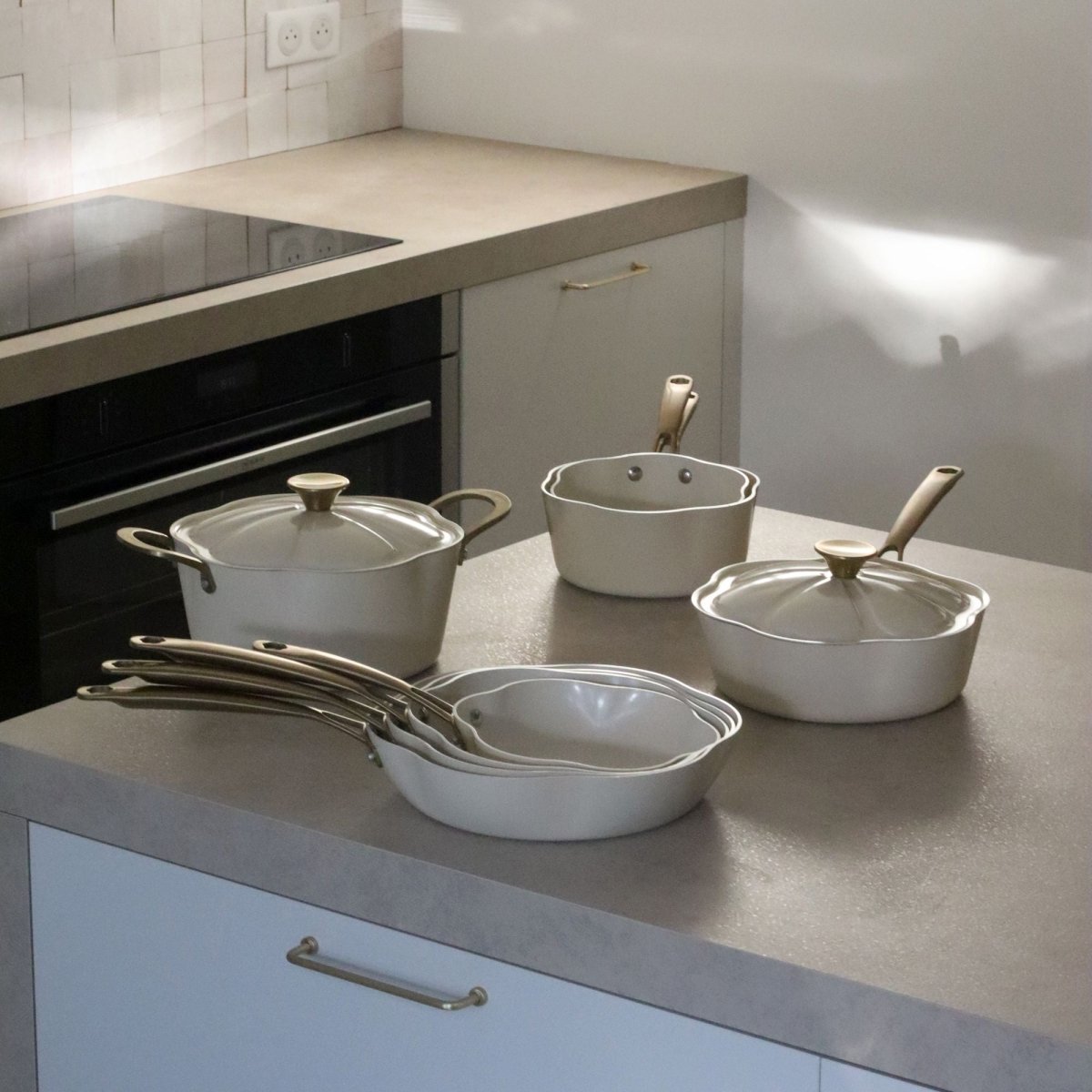 Collection complète gamme Dahlia beige, sauteuse 24 cm et casseroles en aluminium recyclé sur plan de travail moderne