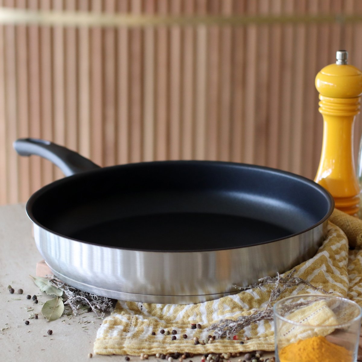 Sauteuse First 24 cm en acier inoxydable avec revêtement antiadhésif noir, vue sur plan de travail avec accessoires cuisine