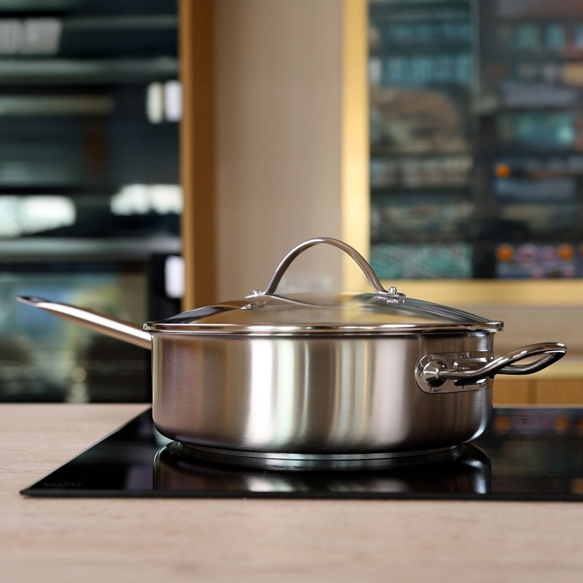 Sauteuse inox professionnelle 28cm avec couvercle en verre posée sur plaque de cuisson en cuisine moderne